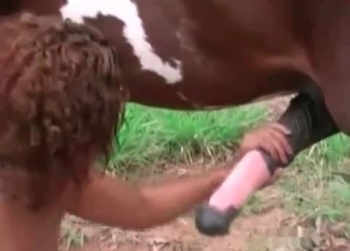 Curly-haired slut jerks off a horse dick